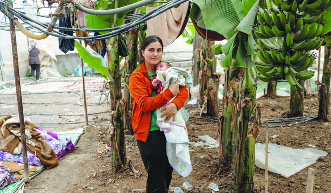 Ozlem Yildirim with her child at a banana plantation in the quake-hit town of Samandag, southern Turkey, where she lives. (AFP)