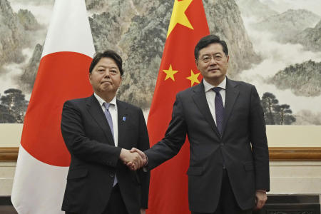 Japanese Foreign Minister Yoshimasa Hayashi (left), shakes hands with his counterpart Qin Gang at the Diaoyutai State Guest House in Beijing, Sunday, April 2, 2023. (Kyodo News via AP)