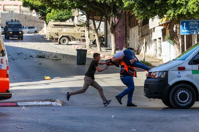 A medic carries an injured man to safety during clashes between Israeli forces and Palestinians following an Israeli army raid in the occupied West Bank city of Nablus on May 4, 2023. (AFP)