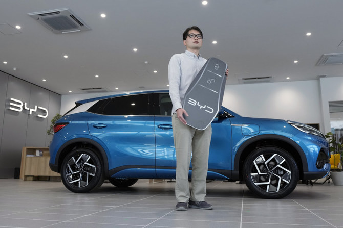 Ohta, who just bought a brand new BYD ATTO 3 electric sports utility vehicle, poses with his car and a symbolically-made key at a BYD dealership on April 4, 2023, in Yokohama near Tokyo. (AP)