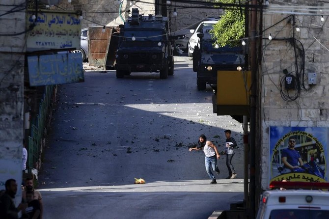 Palestinians take cover as they clash with Israeli forces during an Israeli army raid in the occupied West Bank city of Nablus on May 4, 2023. (AFP)