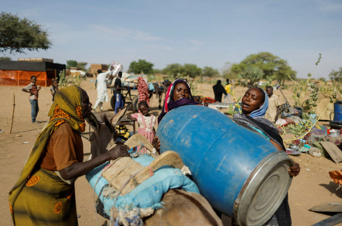 Sudanese refugee women fleeing the violence in their country struggle to load a barrel on a donkey as they prepare to go to the water point, near the border between Sudan and Chad in Koufroun, Chad, on May 7, 2023. (REUTERS/Zohra Bensemra)