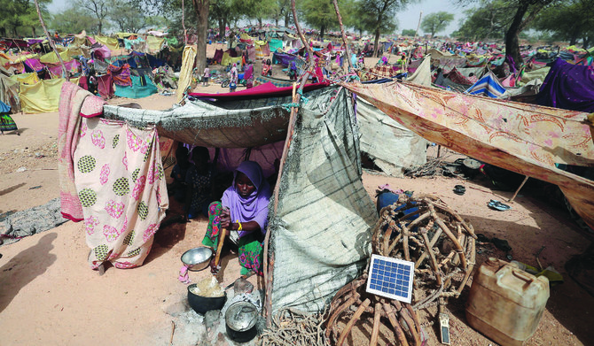 A woman, who fled the conflict in Darfur region, cooks at her makeshift shelter on Saturday near the border between Sudan and Chad. (Reuters)