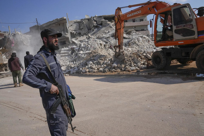 An al-Qaida-linked Hayat Tahrir al-Sham militant stands in front of a destroyed house in Atareb, Syria, Sunday, Feb. 12, 2023. (File/AP