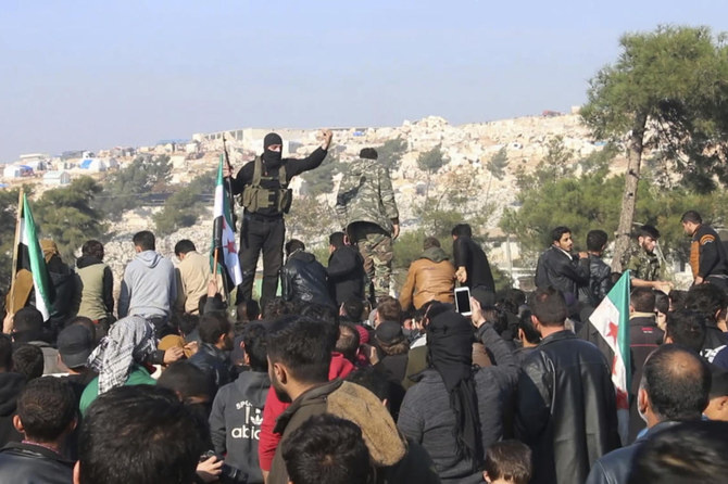 Militants of the Al-Qaida-linked Hayat Tahrir al-Sham try to disperse people who have gathered at the Bab al-Hawa border gate. (File/AP)