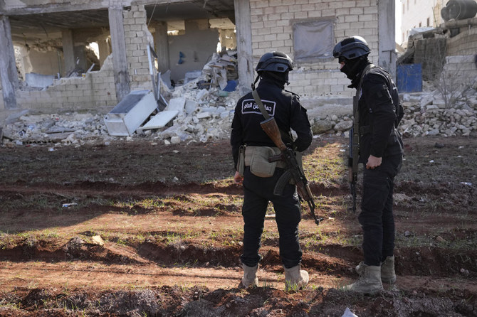 Militants of the al-Qaida-linked Hayat Tahrir al-Sham organization stand in front of a destroyed house in Atareb, Syria, Sunday, Feb. 12, 2023. (AP)