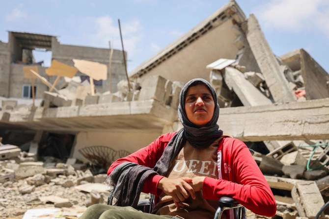A picture taken on May 15, 2023, shows a member of the Palestinian Nabhan family sitting in a wheelchair atop the rubble of their house, in Beit Lahya in the northern Gaza Strip. (AFP)