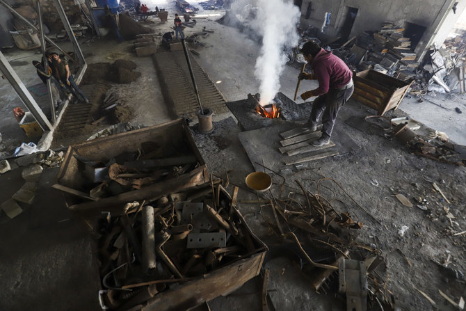 A laborer works at a factory to recycle war remnants and scrap metal near the rebel-held Bab al-Hawa crossing between Syria and Turkey on January 25, 2023. (AFP)