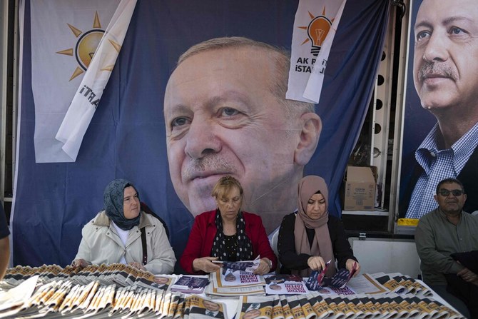 Women sit at a stall in front of a campaign truck bearing a portrait of Turkish President and candidate for his reelection Recep Tayyip Erdogan in Istanbul on May 22, 2023, ahead of on May 28 Turkiye’s presidential run-off. (AFP)