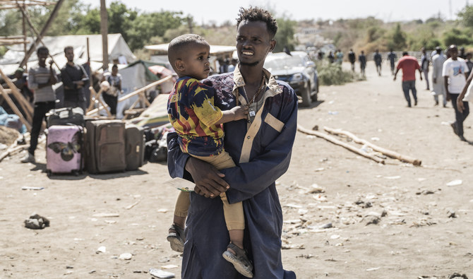 A man carries a child as refugees from Sudan cross into Ethiopia in Metema, on May 4, 2023. (AFP)