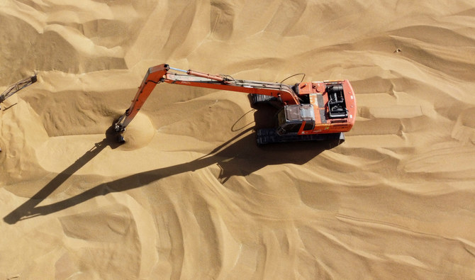 An excavator collecting wheat grains at a silo in Karbala, Iraq on May 15, 2023. (Reuters)