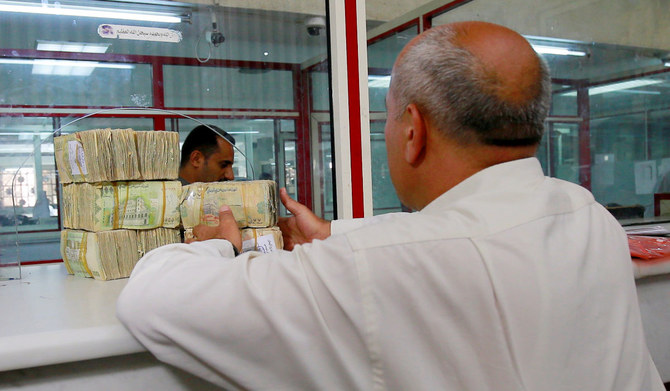 A man receives bands of Yemeni riyal banknotes at the Houthi-run Central Bank of Yemen in Sanaa, Yemen June 30, 2021. (REUTERS)