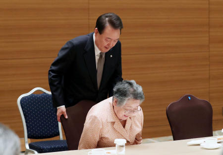 South Korea’s President Yoon Suk-Yyeol helps a South Korean survivor of the 1945 atomic bombing in the Japanese city of Hiroshima, in Hiroshima, Japan, May 19, 2023. (Yonhap via Reuters)