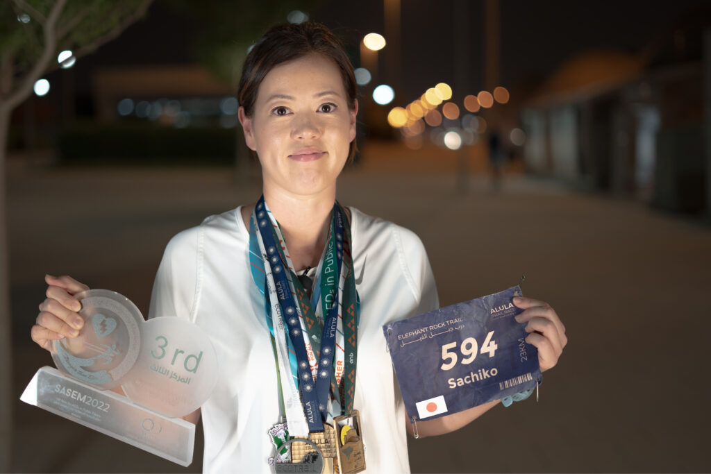 Sachiko Talbi showing her medals and running badge from AUla's Elephant Rock Trail Race.  (AN Photo: Huda Bashatah)