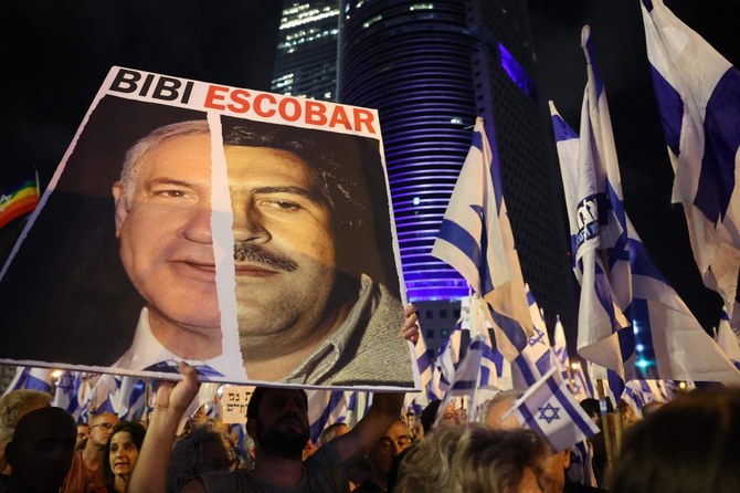 A man lifts a placard depicting Israeli Prime Minister Benjamin Netanyahu and deceased drug lord Pablo Escobar as they protest the hard-right government’s controversial judicial reform plans, in Tel Aviv on June 10, 2023. (AFP)