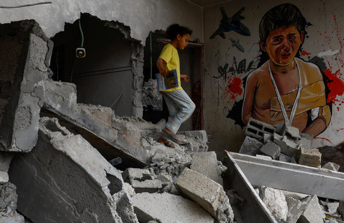Palestinian girl walks past a graffiti drawn by Palestinian artists on a house destroyed by Israel in Deir Al-Balah in the central Gaza Strip. (Reuters)