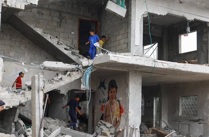 Palestinian children walk near a graffiti, as artists draw graffiti on houses destroyed by Israel in recent Israeli-Gaza fighting, in Deir Al-Balah, central Gaza Strip. (Reuters)