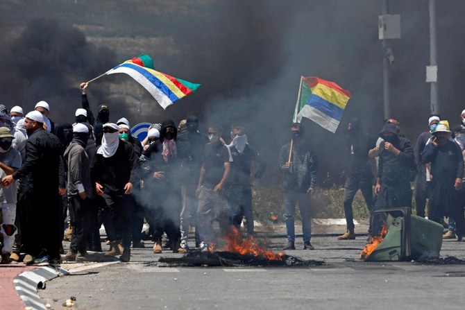 Members of the Druze community wave flags during a protest in their village of Masada in the Israel-annexed Golan Heights on June 21, 2023, against an Israeli wind turbine project reportedly planned in agricultural lands of the village. (AFP)