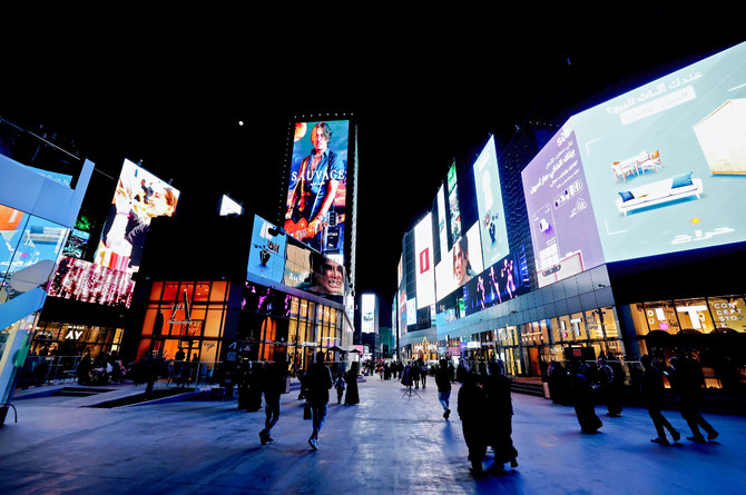 People walk beneath advertisement billboards at Boulevard entertainment city in the Saudi capital Riyadh. (File/AFP)