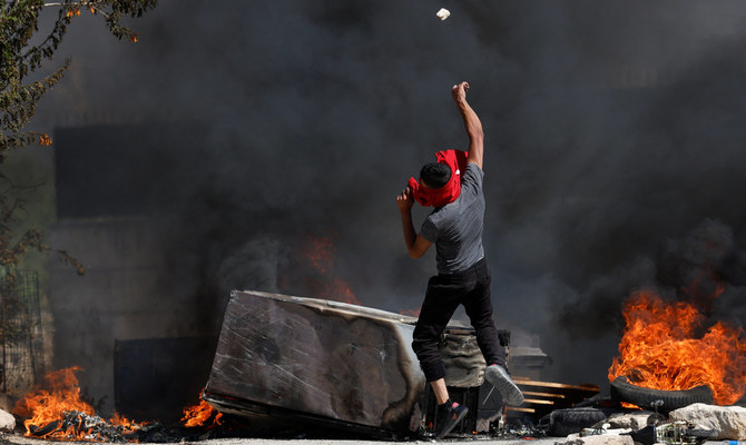 A Palestinian throws a stone during clashes with Israeli troops after Israeli settlers attack Umm Safa village near Ramallah, in the Israeli-occupied West Bank, June 24, 2023. (Reuters)