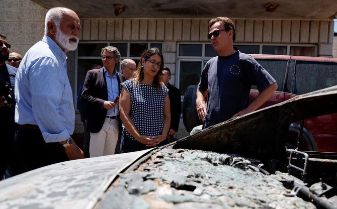 A European diplomat stands near a burned car, as he checks Palestinian houses that were torched by Israeli settlers, during a visit to Turmus Ayya, West Bank, June 23, 2023. (Reuters)