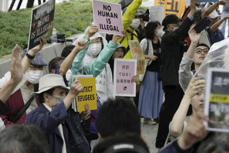 Protesters gather outside the parliament in which a revision to an immigration and refugee law was approved, in Tokyo, Friday, June 9, 2023. (Kyodo News via AP)