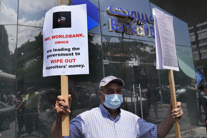 A protester holds placards outside Bank of Beirut during a protest demanding the release of depositors' trapped savings, in Beirut, Lebanon. (File/AP)