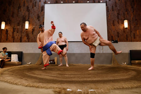 Former sumo wrestlers Kotoohtori, 40, and Towanoyama, 45, demonstrate a sumo ritual with a Mexican tourist, who is wearing a sumo wrestler’s costume, in the sumo ring at Yokozuna Tonkatsu Dosukoi Tanaka in Tokyo, Japan June 30, 2023. (Reuters)