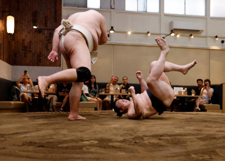 Former sumo wrestlers Kotoohtori, 40, and Towanoyama, 45, engage in sparring before tourists from abroad. (Reuters)