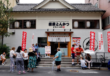 Tourists from abroad wait for Yokozuna Tonkatsu Dosukoi Tanaka, a sumo wrestling themed restaurant to open, in Tokyo, Japan June 30, 2023. (Reuters)