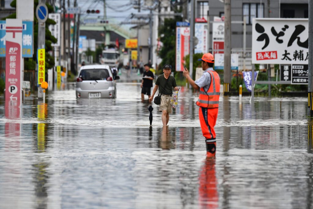 Residents manoeuver through a flooded street in the city of Kurume, Fukuoka prefecture, on July 10, 2023 (AFP). 