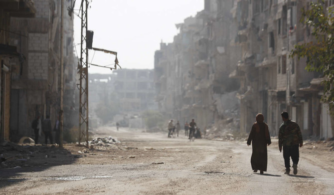 People walk under Palestinian flags in Yarmouk camp in Damascus Syria. (AP)