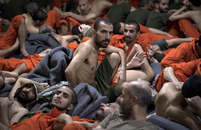 Men, accused of being affiliated with Daesh, sit on the floor in a prison in the northeastern Syrian city of Hasakeh on October 26, 2019. (AFP)