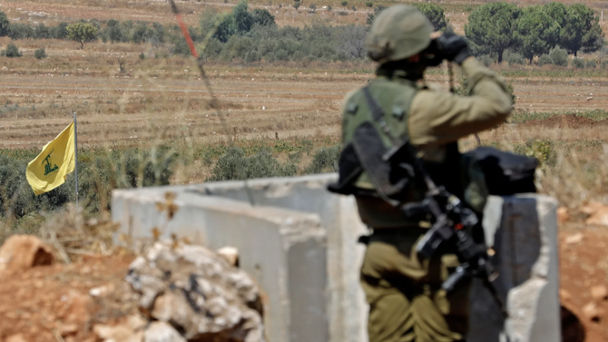 In this file photo, Israeli soldiers stand position in northern Israel along the border with Lebanon near a Hezbollah flag in Sept. 2022. (AFP/File Photo)