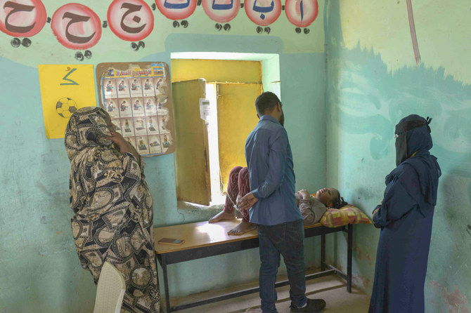 Relatives stand by a patient at a makeshift emergency room installed by Sudanese volunteers in a school building in Omdurman, the capital's twin city, on May 27, 2023, amid fighting between the forces of two rival generals. (AFP)