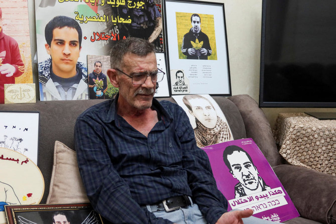 Kheiry Al-Halaq, the father of Iyad Al-Halaq, an unarmed autistic Palestinian man who was shot dead by Israeli police, sits surrounded by pictures of his son, East Jerusalem, July 6, 2023. (Reuters)