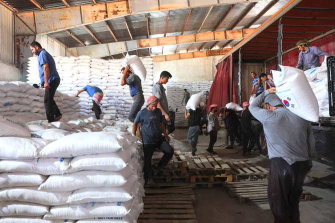 Workers unload bags of aid at a warehouse near the Syrian Bab Al-Hawa border crossing with Turkey. (AFP)