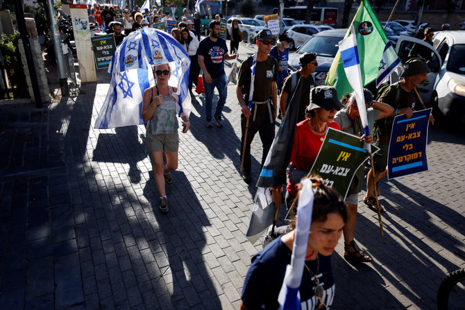 Israelis take part in a protest where military reservists sign pledge to suspend voluntary military service if the government passes judicial overhaul legislation near the defense ministry in Tel Aviv, Israel, on July 19, 2023. The placard in Hebrew reads 