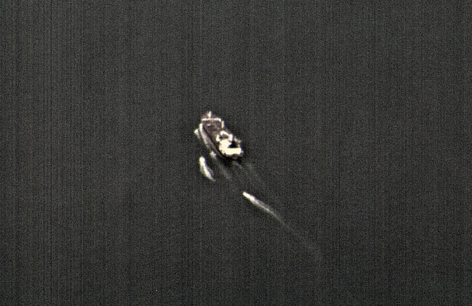 This still image taken from surveillance video from a US Navy Boeing P-8 Poseidon shows three Iranian Revolutionary Guard fast-attack vessels near a commercial ship in the Strait of Hormuz on June 4, 2023. (US Navy via AP, File)