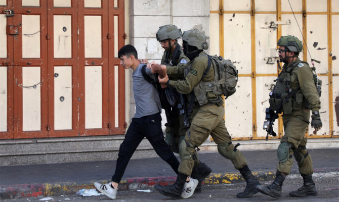 Israeli soldiers detain a Palestinian youth in the Bab Al-Zawiya area in the Palestinian city of Hebron in the occupied West Bank. (AFP/File)