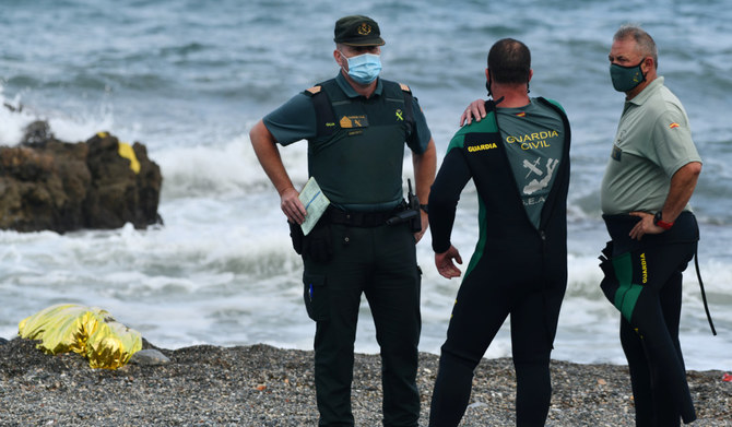 Spanish Guardia Civil members stand next to the body of a migrant at the beach of the Spanish enclave of Ceuta on May 20, 2021. (AFP)