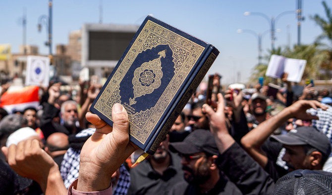 A demonstrator holds a copy of the Holy Qur’an during a rally after the weekly Friday prayers denouncing the burning of the Qur’an in Sweden, in Iraq on July 21, 2023. (AFP)