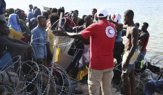 Migrants gather near the Libyan-Tunisia border, as Libyan security forces and Libyan Red Cross workers distribute food aid to them on Sunday, July 23, 2023. (AP)