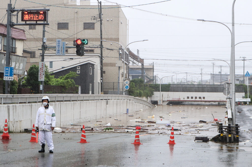 An official stands guard to stop traffic at the entrance to an underpass which flooded due to heavy rains across northern Japan, in Akita on July 16. (AFP)