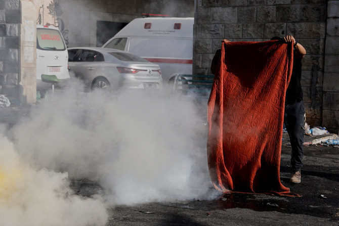 Palestinian carries blanket to protect himself from gas during clashes between Palestinians and Israeli forces amid an Israeli military operation, in Jenin. (File/Reuters)