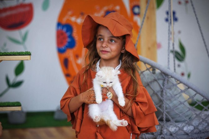 A girl holds a feline at the newly inaugurated Cat Cafe in Gaza City. (AFP)