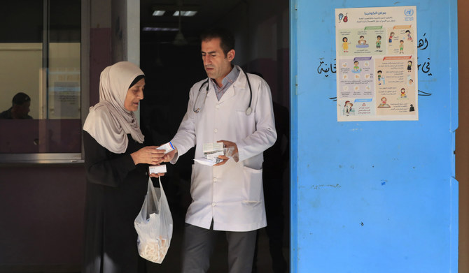 A Palestinian woman received medicine from a doctor at a clinic run by the agency for Palestinian refugees, or UNRWA, in the Ein el-Hilweh refugee camp in the southern port city of Sidon, Lebanon, Tuesday, June 20, 2023. (AP)