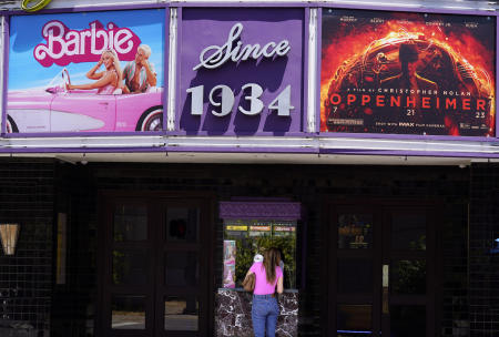 A patron buys a movie ticket underneath a marquee featuring the films 