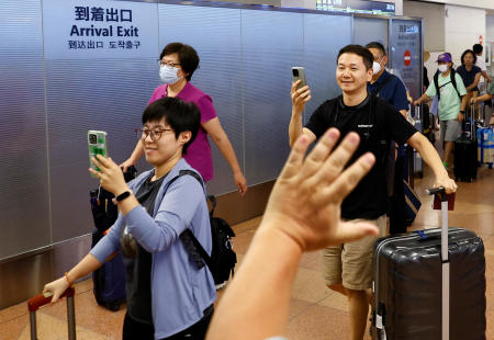 A man waves his hand to a Chinese tour group from Beijing upon their arrival at Haneda airport in Tokyo, August 23, 2023. (Reuters)