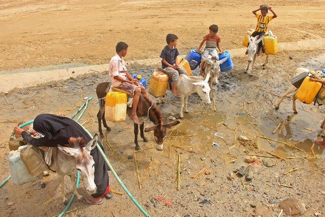 Boys riding donkeys queue to fill their containers amidst a shortage of water and soaring temperatures in Yemen on July 31, 2023. (AFP)